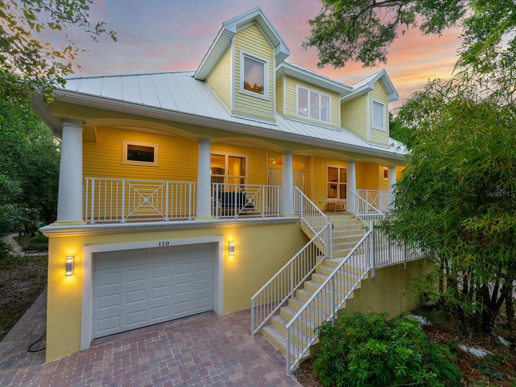 A yellow two-story house with a white garage door, front porch, and exterior staircase — 110 OCEAN WAY DRIVE, PONCE INLET, FL