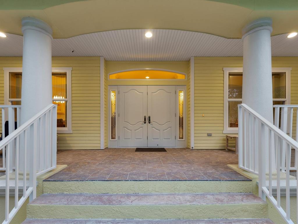 A yellow house exterior features a tiled front porch with white railings and double doors — 110 OCEAN WAY DRIVE, PONCE INLET, FL