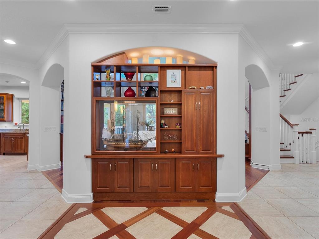 A living room features high ceilings, floor-to-ceiling bookshelves, a rolling ladder, and hardwood floors — 110 OCEAN WAY DRIVE, PONCE INLET, FL