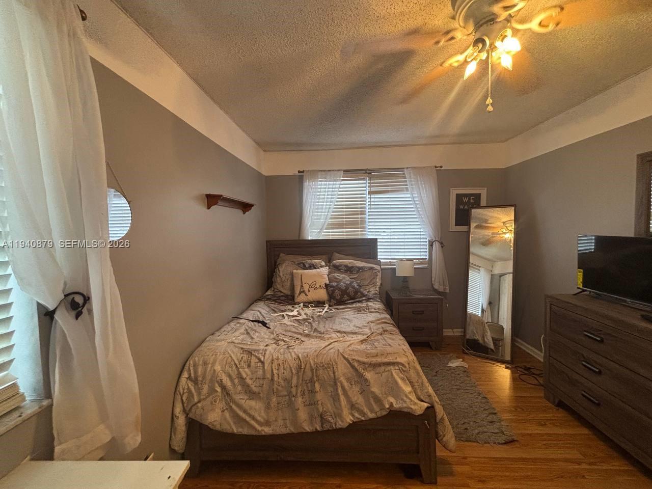 A bedroom features a bed with patterned bedding, a wooden dresser, and a floor mirror — 7390 S Pinewalk Dr S, Margate FL 33063, MARGATE, FL