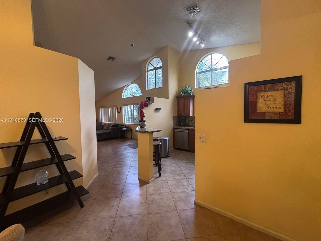 A living room and kitchen area with vaulted ceilings, tiled floors, and arched windows — 7390 S Pinewalk Dr S, Margate FL 33063, MARGATE, FL