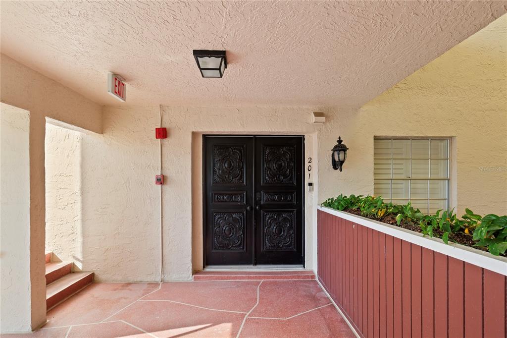 A covered entryway features double doors, a red tiled floor, and a red planter box — 2900 GULF BOULEVARD UNIT 201, BELLEAIR BEACH, FL