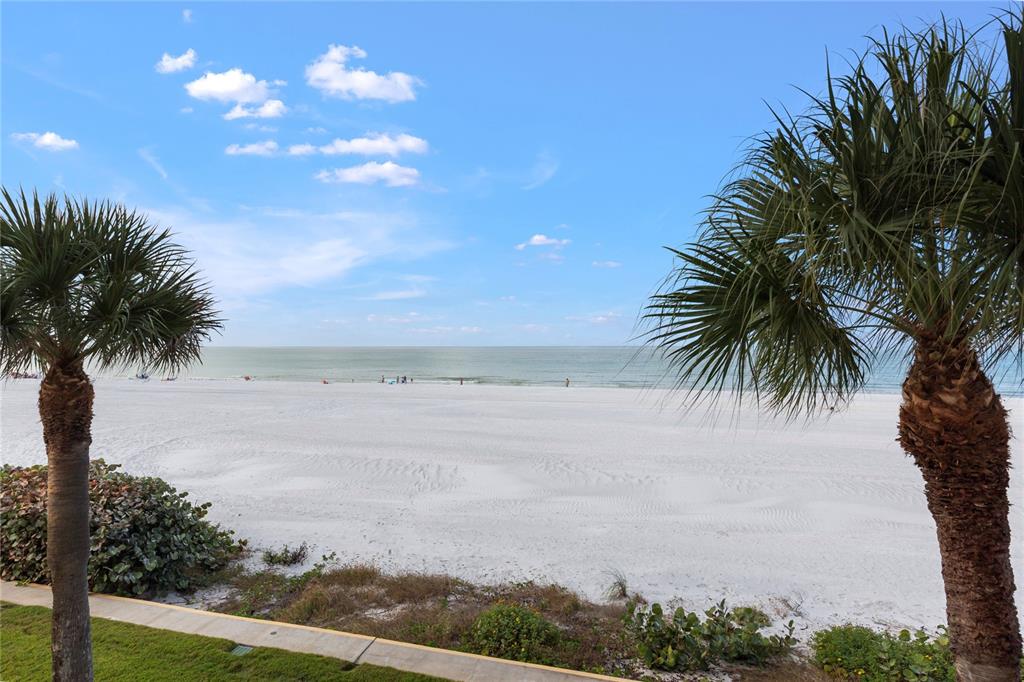 A view of a white sand beach and the ocean framed by two palm trees — 2900 GULF BOULEVARD UNIT 201, BELLEAIR BEACH, FL