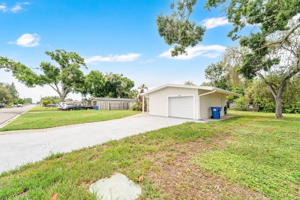 A single-story house exterior with a tan stucco facade, brown front door, and brick walkway — 1920 64TH AVENUE N, ST PETERSBURG, FL