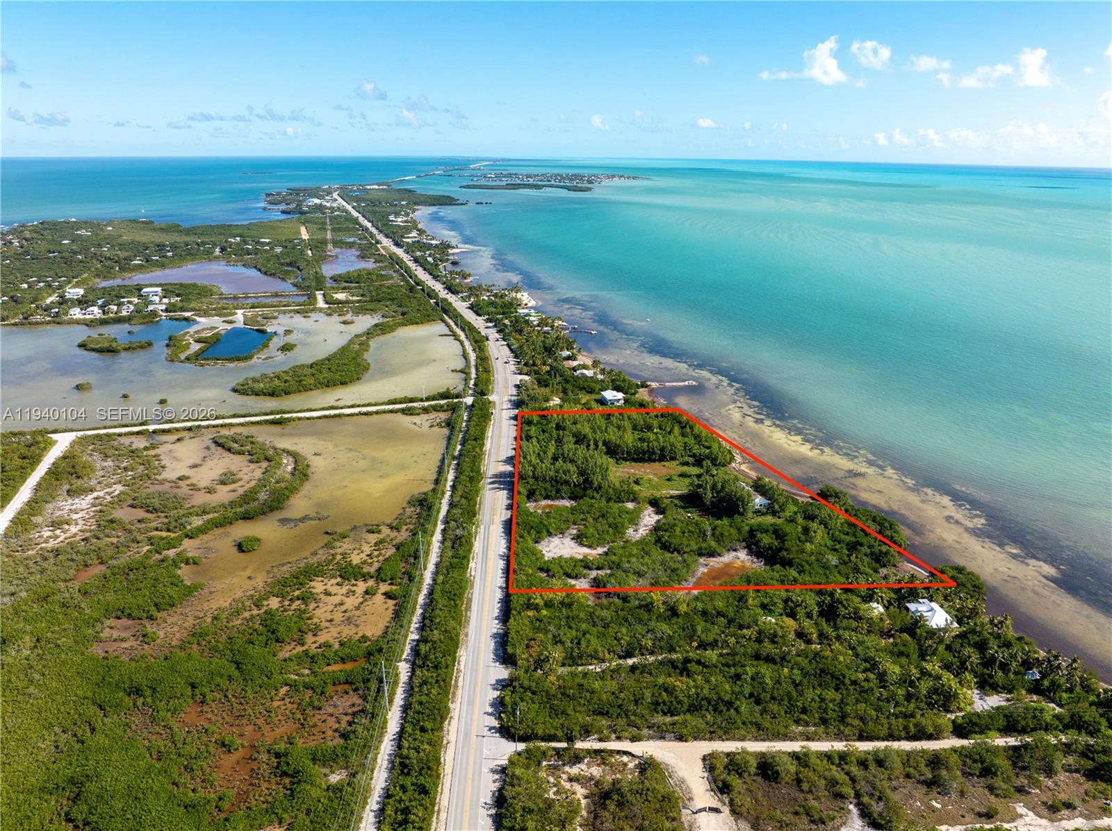 An aerial view shows a vacant, rectangular waterfront lot outlined in red along a highway — 57478 Overseas Hwy, Marathon FL 33050, MARATHON, FL