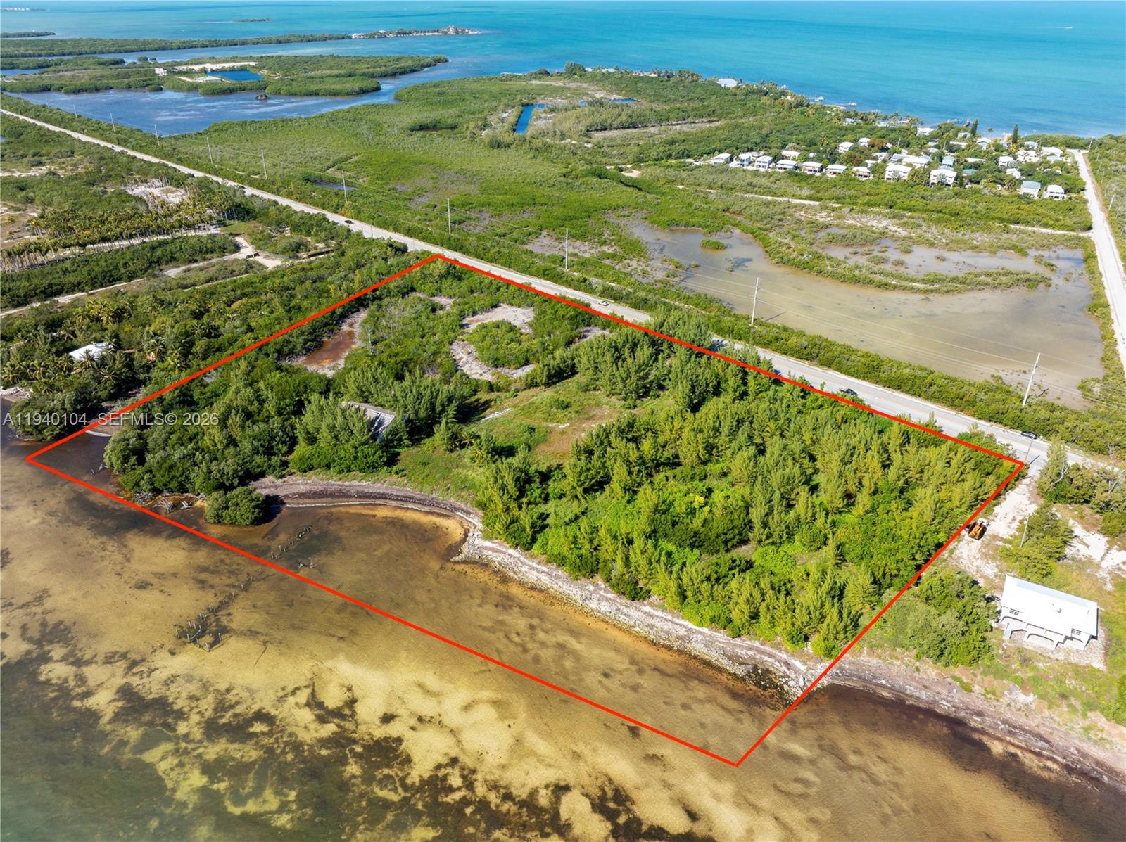 An aerial view shows a rectangular, undeveloped waterfront lot outlined in red along a road — 57478 Overseas Hwy, Marathon FL 33050, MARATHON, FL