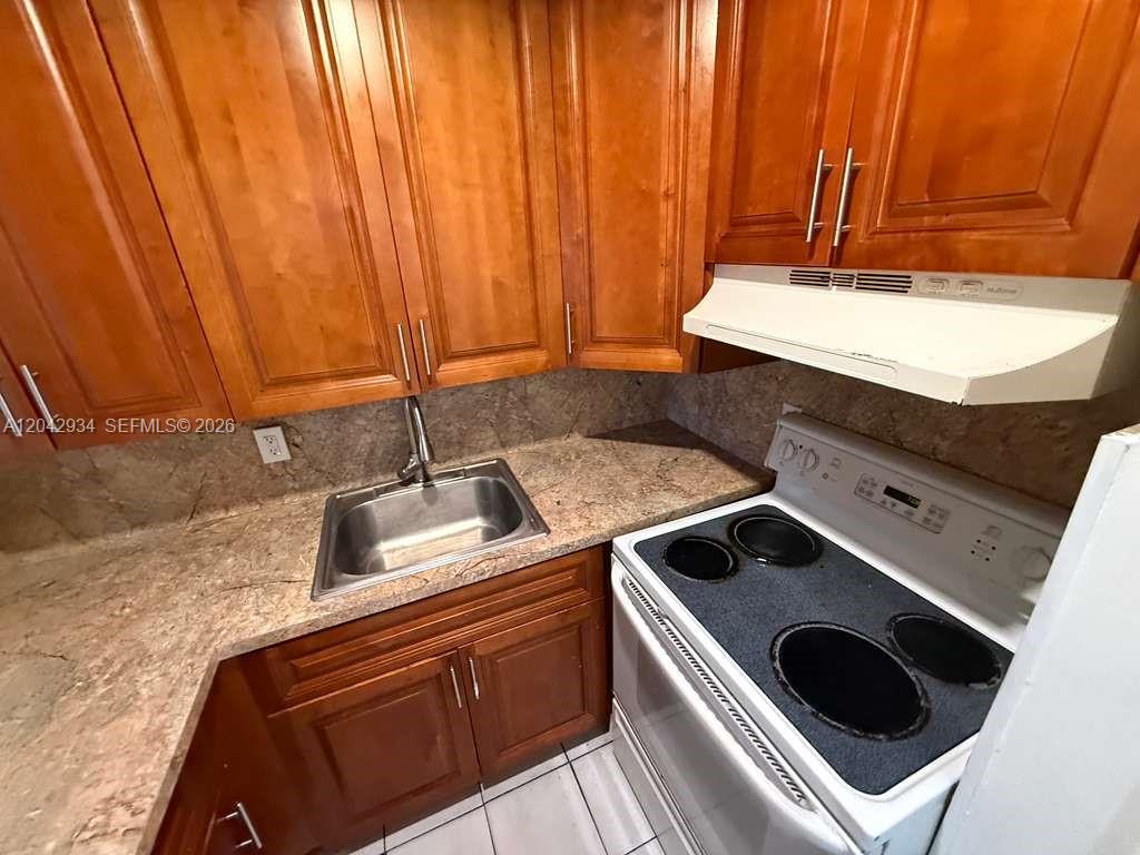A kitchen features wood cabinets, granite countertops, a stainless steel sink, and a white stove — 4370 NW 11th St # 214, Miami FL 33126, MIAMI, FL