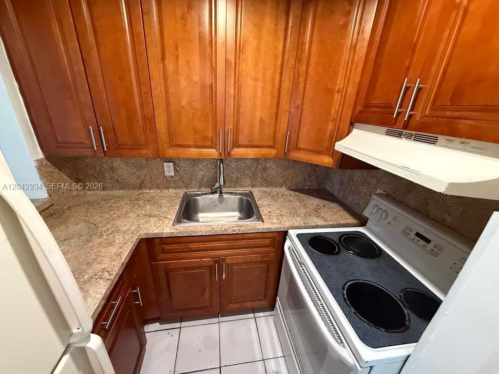A kitchen features wood cabinets, a stainless steel sink, and a white electric stove — 4370 NW 11th St # 214, Miami FL 33126, MIAMI, FL