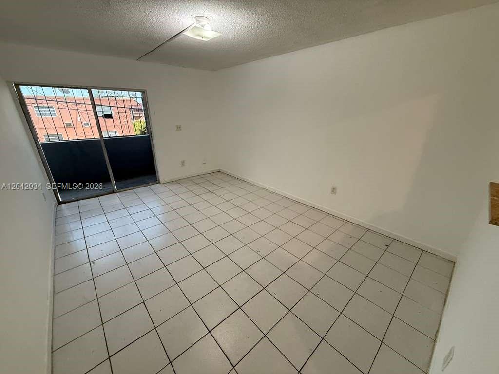 An empty room features white walls, white tile flooring, and a sliding glass balcony door — 4370 NW 11th St # 214, Miami FL 33126, MIAMI, FL