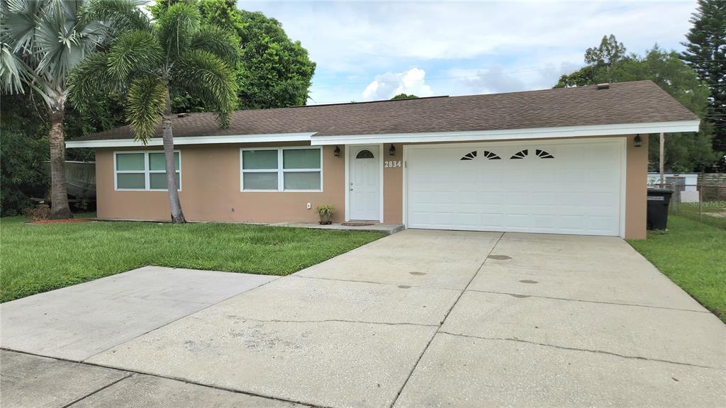 A single-story house with a tan exterior, a white garage door, and a palm tree — 2834 STATE ROAD 590, CLEARWATER, FL
