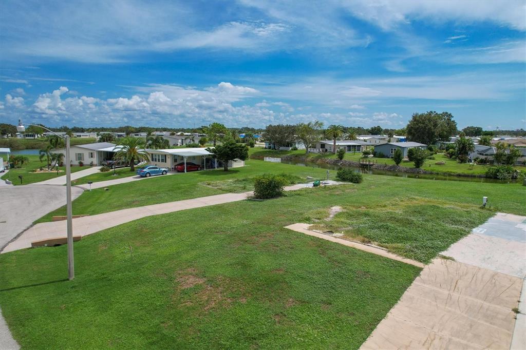 An elevated view of a grassy residential lot with a concrete driveway and a canal — 1308 SANDERLING DRIVE, ENGLEWOOD, FL