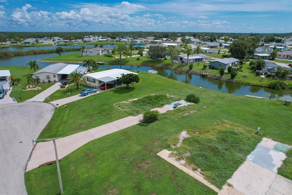 An aerial view shows a vacant lot with a concrete driveway next to waterfront homes — 1308 SANDERLING DRIVE, ENGLEWOOD, FL