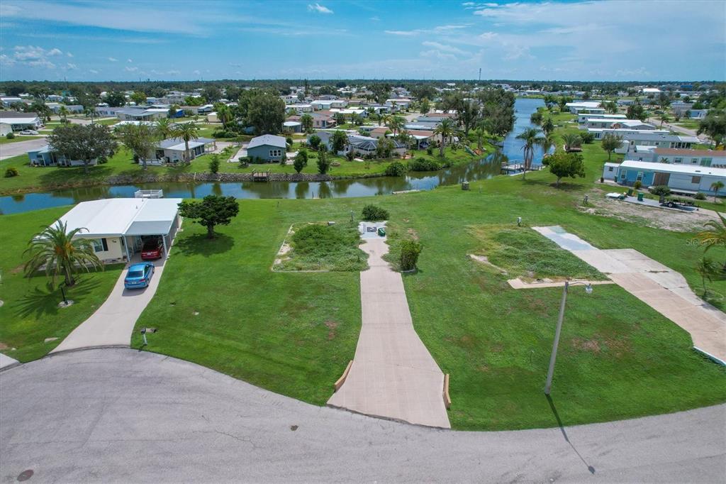 An aerial view shows a vacant residential lot with a concrete driveway beside a canal — 1308 SANDERLING DRIVE, ENGLEWOOD, FL