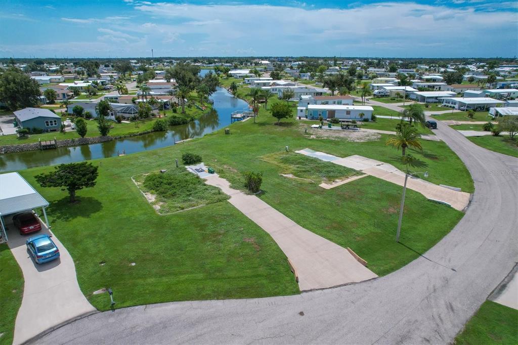 An aerial view shows two vacant residential lots with concrete driveways next to a canal — 1308 SANDERLING DRIVE, ENGLEWOOD, FL