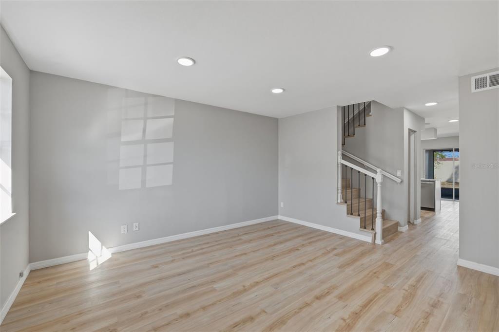 An interior view of a living room with light wood flooring and a staircase — 6600 121ST AVENUE N UNIT 3, LARGO, FL
