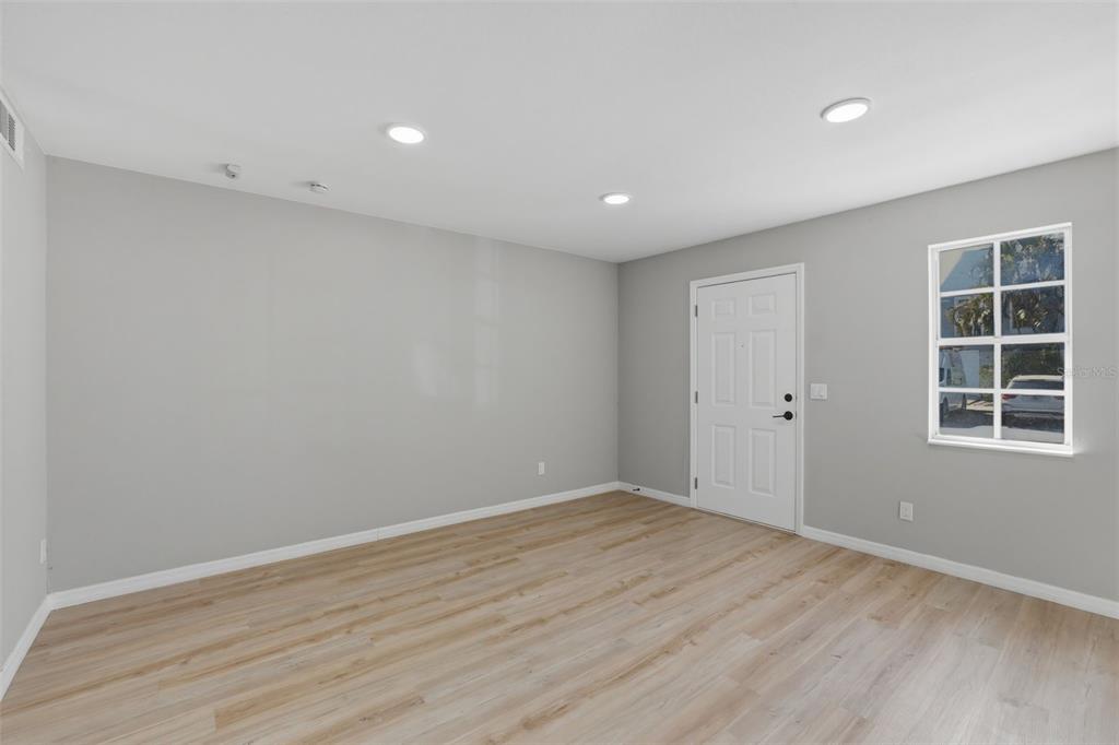 An empty room with light gray walls, wood-look flooring, recessed lighting, and a white door — 6600 121ST AVENUE N UNIT 3, LARGO, FL