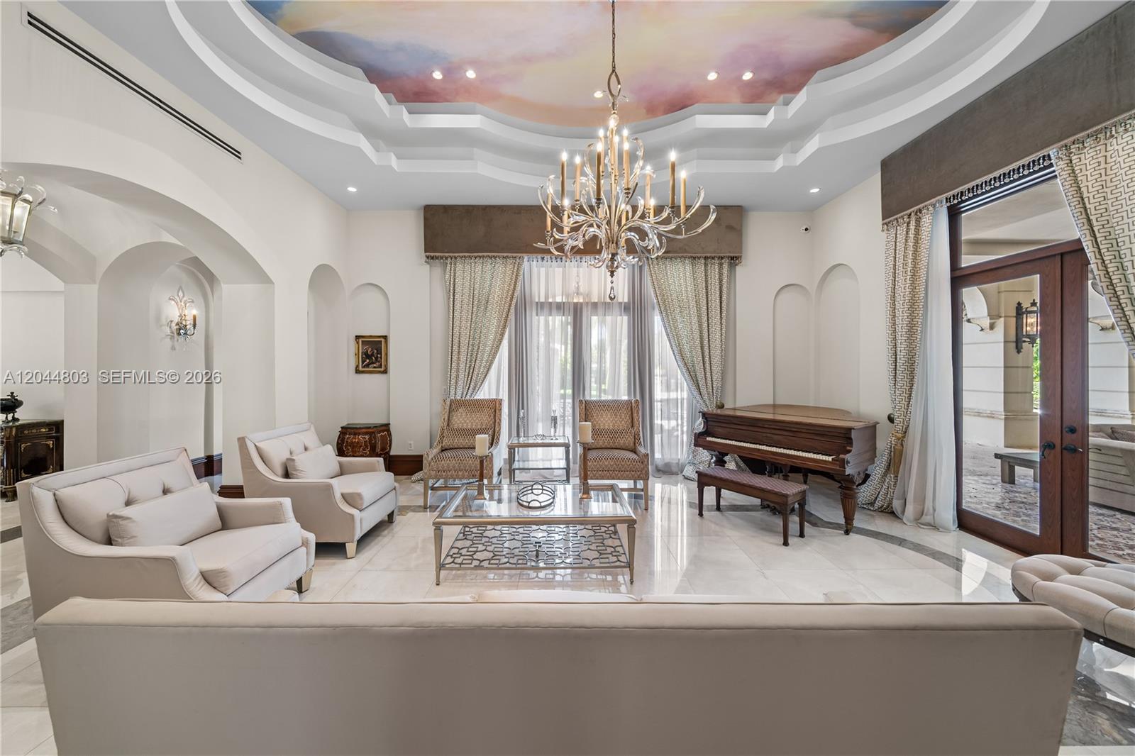 A formal living room features a grand piano, a crystal chandelier, and a painted ceiling — 150 Edgewater Dr, Coral Gables FL 33133, CORAL GABLES, FL