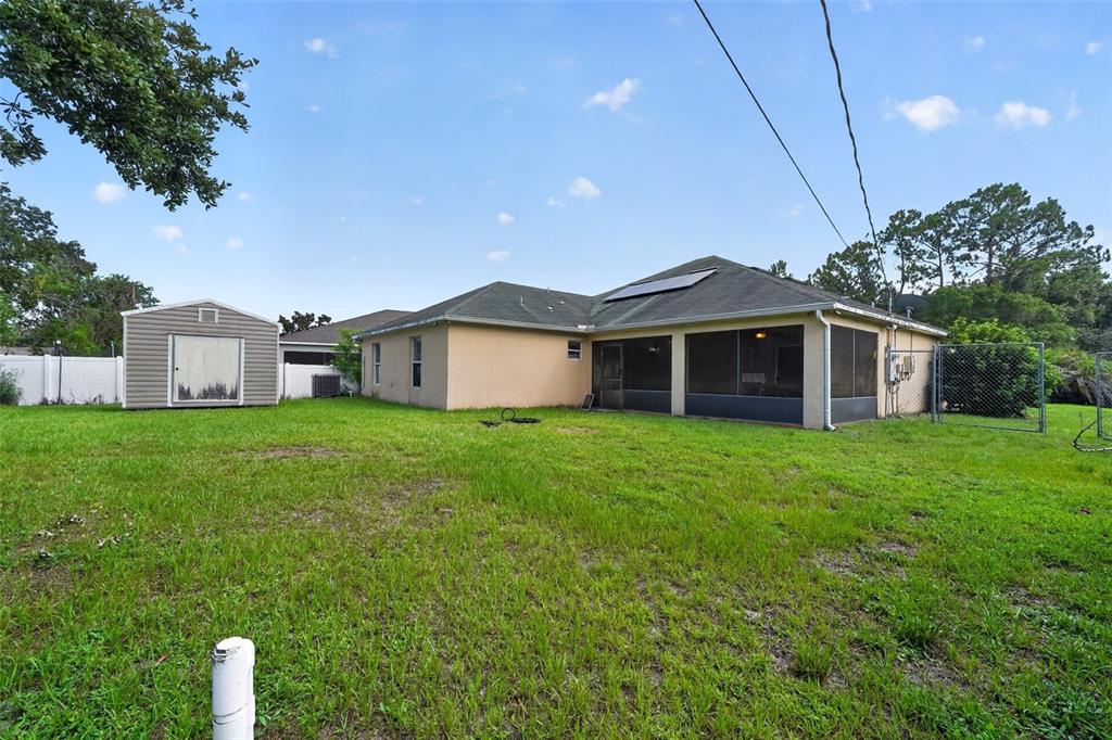 The backyard features a tan house with a screened-in porch, a shed, and fencing — 1081 JOHNSTON ROAD SE, PALM BAY, FL