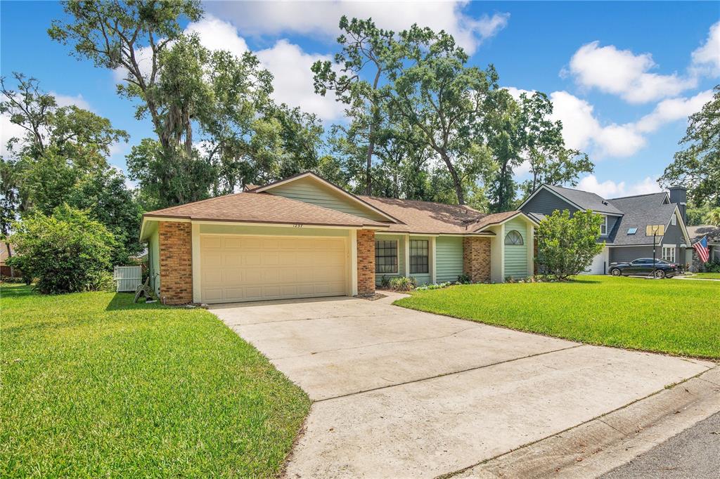 A single-story house with light green siding, a brick facade, and a two-car garage — 1237 LEATHERWOOD DRIVE, ALTAMONTE SPRINGS, FL