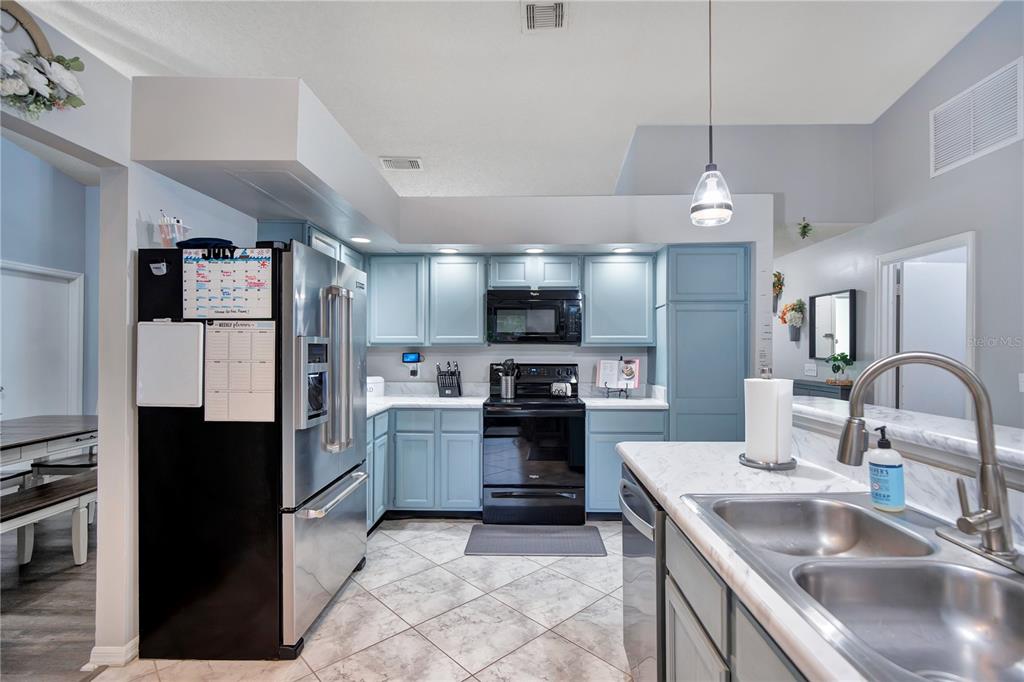 A kitchen features light blue cabinets, stainless steel appliances, and white marble-look countertops — 1237 LEATHERWOOD DRIVE, ALTAMONTE SPRINGS, FL