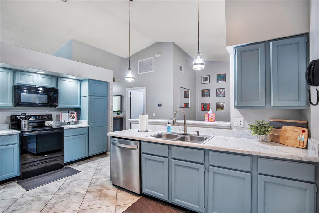 A kitchen features blue cabinets, stainless steel appliances, and white marble-look countertops — 1237 LEATHERWOOD DRIVE, ALTAMONTE SPRINGS, FL