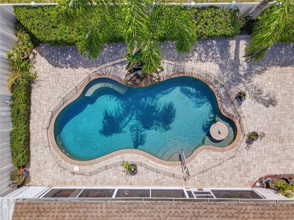 An aerial view shows a freeform swimming pool with a spa inside a fenced patio — 4300 ONORIO STREET, NEW PORT RICHEY, FL