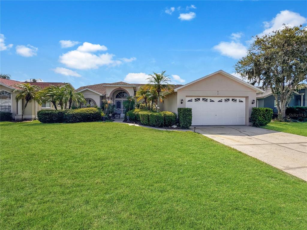 A single-story suburban house with a white garage, arched entryway, and a large front lawn — 4300 ONORIO STREET, NEW PORT RICHEY, FL