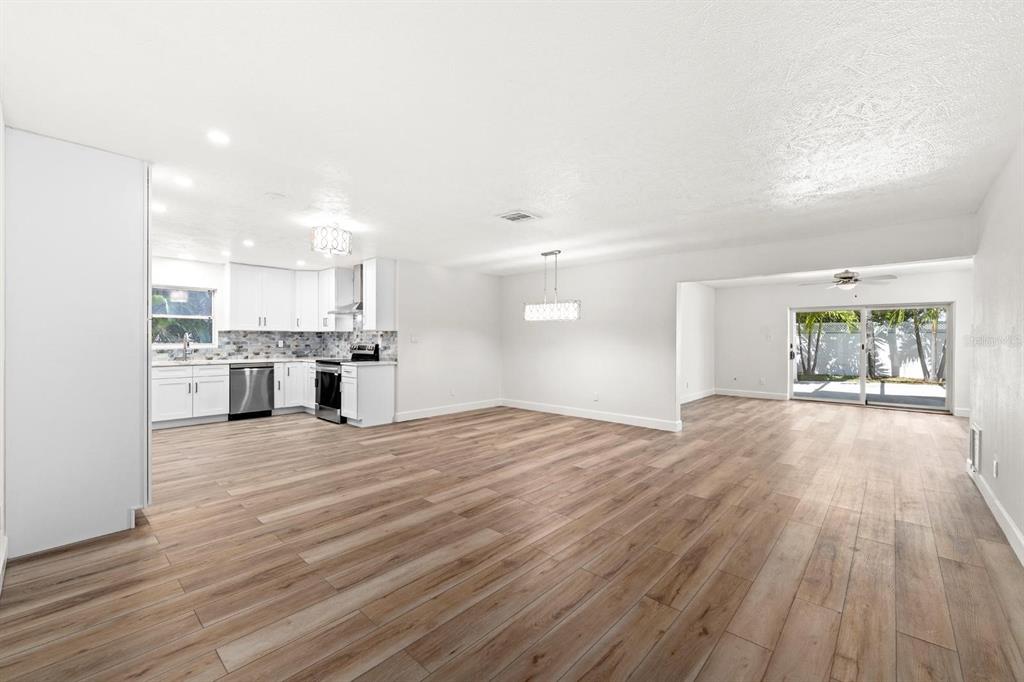 An open-concept kitchen and living area featuring white cabinets, stainless appliances, and wood-look flooring — 4540 BAYSHORE BOULEVARD NE, ST PETERSBURG, FL