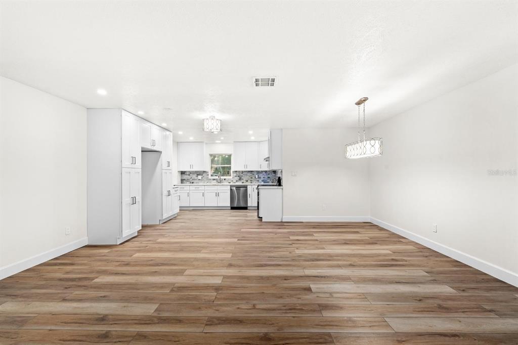 A bright, open-concept kitchen and dining area features white cabinetry and wood-look flooring — 4540 BAYSHORE BOULEVARD NE, ST PETERSBURG, FL
