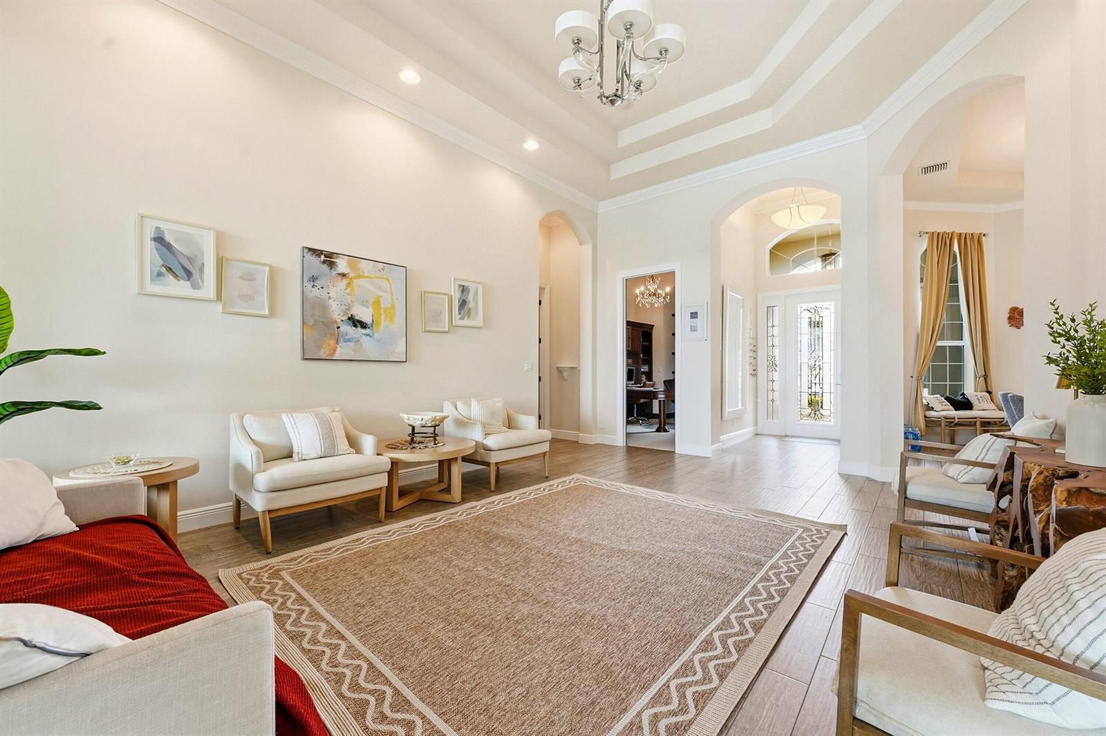 A bright living room features a tray ceiling, tile flooring, and a central area rug — 851 Edgebrook Lane, West Palm Beach FL 33411, WEST PALM BEACH, FL