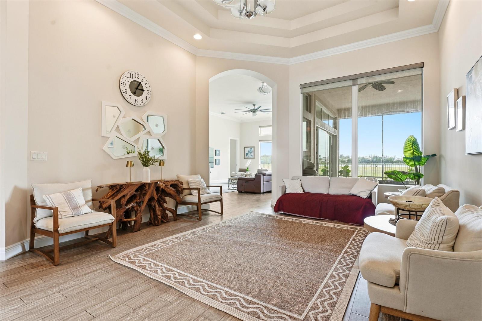 A bright living room features a large area rug, wood-look tile floors, and arched doorways — 851 Edgebrook Lane, West Palm Beach FL 33411, WEST PALM BEACH, FL