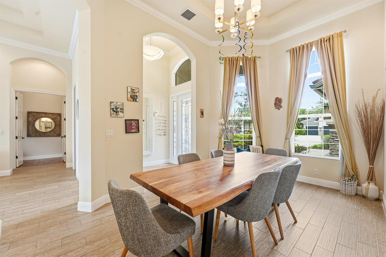 A dining room features a wooden table, gray chairs, and large windows with tan curtains — 851 Edgebrook Lane, West Palm Beach FL 33411, WEST PALM BEACH, FL