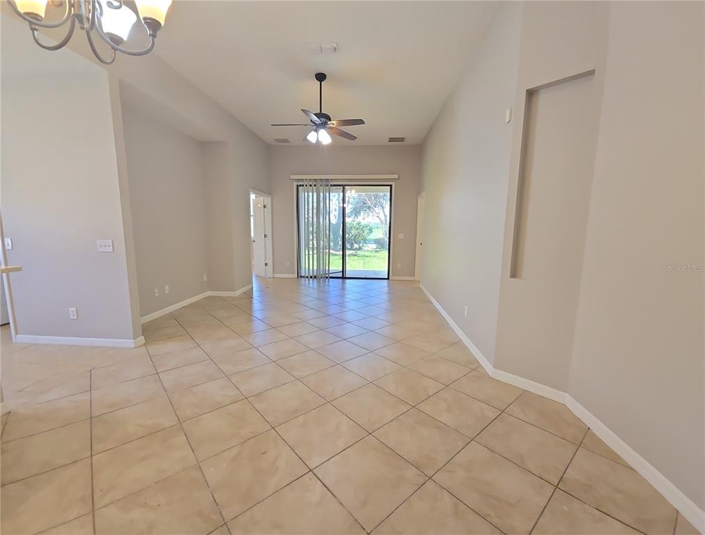 A living area with light-colored tile flooring, a ceiling fan, and sliding glass patio doors — 5201 SUNSET CANYON DRIVE, KISSIMMEE, FL
