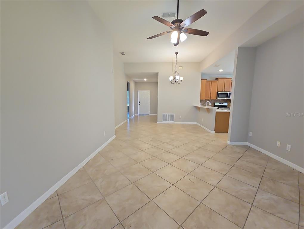An open-concept dining area with tile flooring, a ceiling fan, and a kitchen breakfast bar — 5201 SUNSET CANYON DRIVE, KISSIMMEE, FL