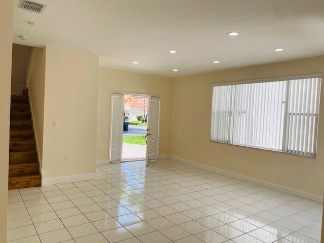 A bright living room features white tile flooring, recessed lighting, a staircase, and glass doors — 3145 N 37th Avenue, Hollywood FL 33021, HOLLYWOOD, FL