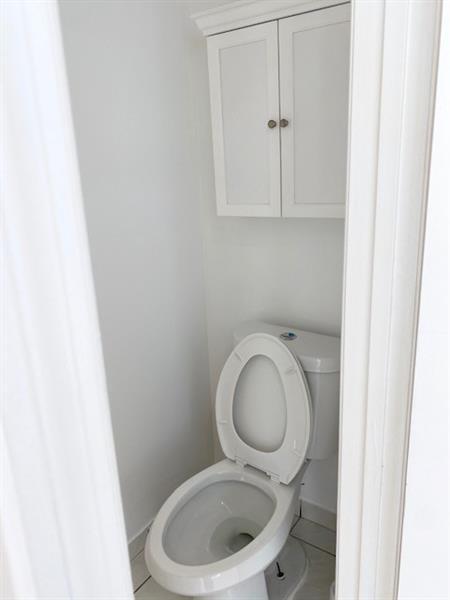 A small bathroom features a white toilet and a wall-mounted white cabinet above it — 3145 N 37th Avenue, Hollywood FL 33021, HOLLYWOOD, FL