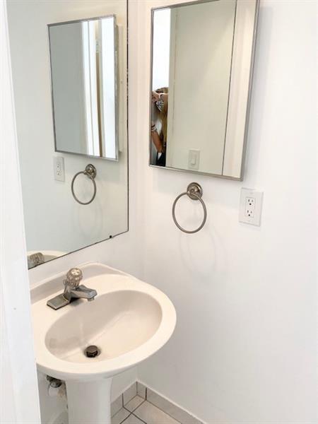 A white pedestal sink sits below two rectangular mirrors and two towel rings in a bathroom — 3145 N 37th Avenue, Hollywood FL 33021, HOLLYWOOD, FL