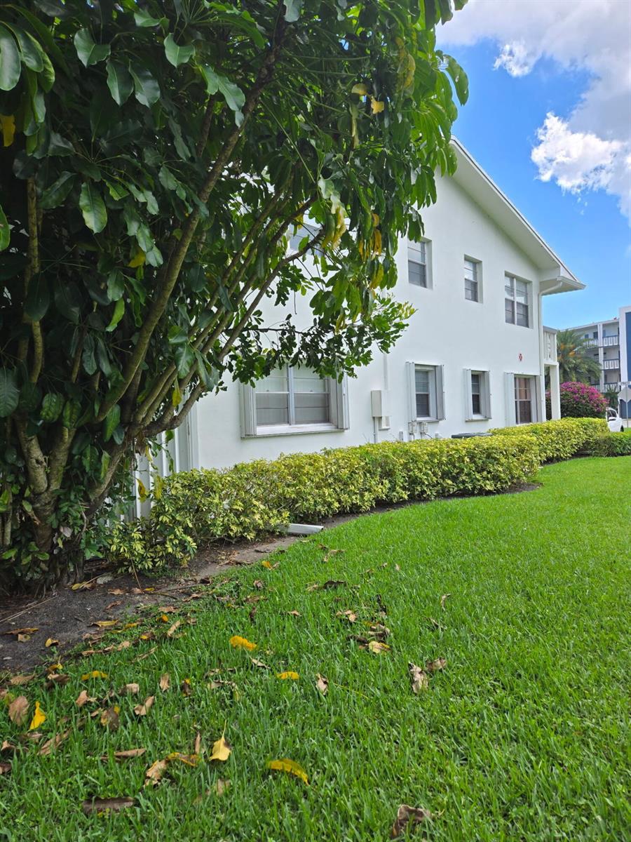 A white two-story apartment building is surrounded by a green lawn and a large tree — 177 Upminster I # 177, Deerfield Beach FL 33442, DEERFIELD BEACH, FL