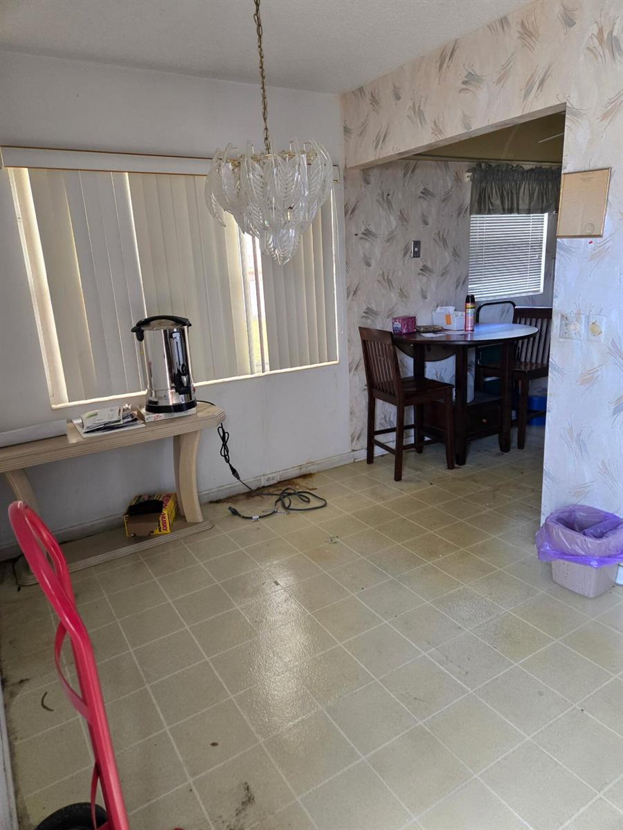 A dining area features a glass chandelier, vinyl tile flooring, and wallpapered walls — 177 Upminster I # 177, Deerfield Beach FL 33442, DEERFIELD BEACH, FL