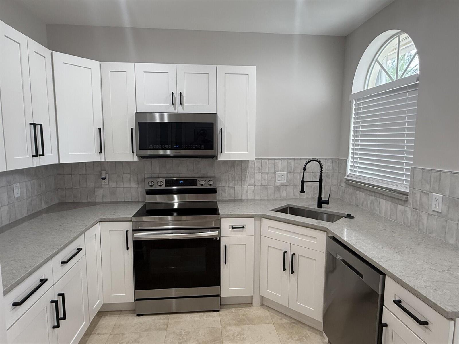 A kitchen features white cabinets, stainless steel appliances, gray countertops, and a subway tile backsplash — 7218 Panache Way, Boca Raton FL 33433, BOCA RATON, FL