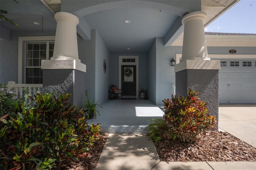 The front entrance of a house features a covered porch with two columns and landscaping — 5029 TORREY HILLS LANE, LUTZ, FL