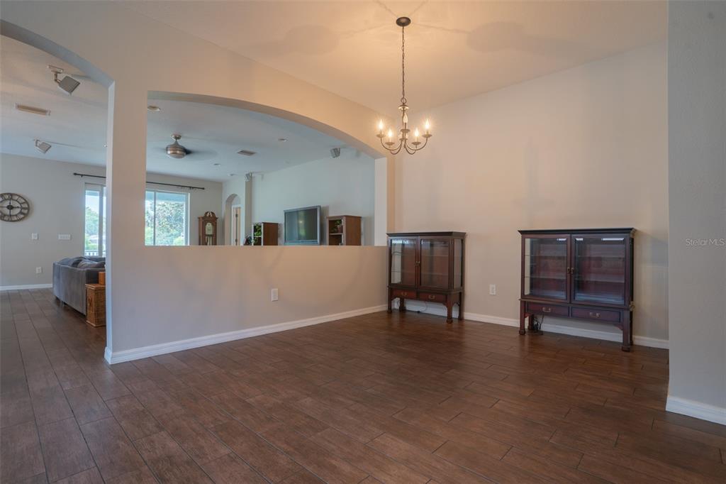 A dining area with wood-look tile flooring, an arched wall opening, and a chandelier — 5029 TORREY HILLS LANE, LUTZ, FL