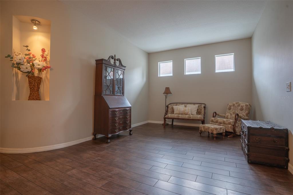 A living room with wood-look tile flooring, a built-in wall niche, and three high windows — 5029 TORREY HILLS LANE, LUTZ, FL