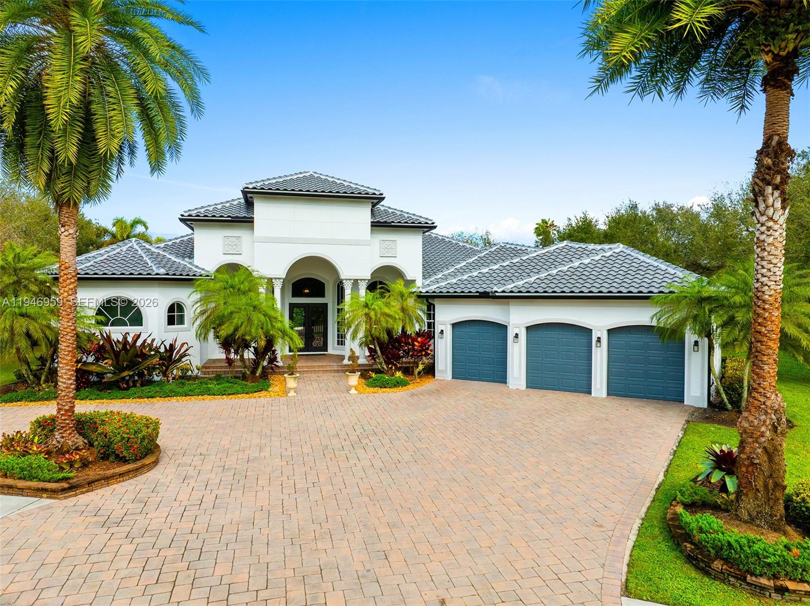 A white house with a tile roof, three-car garage, and a paved driveway — 12401 N Stonebrook Cir, Davie FL 33330, DAVIE, FL