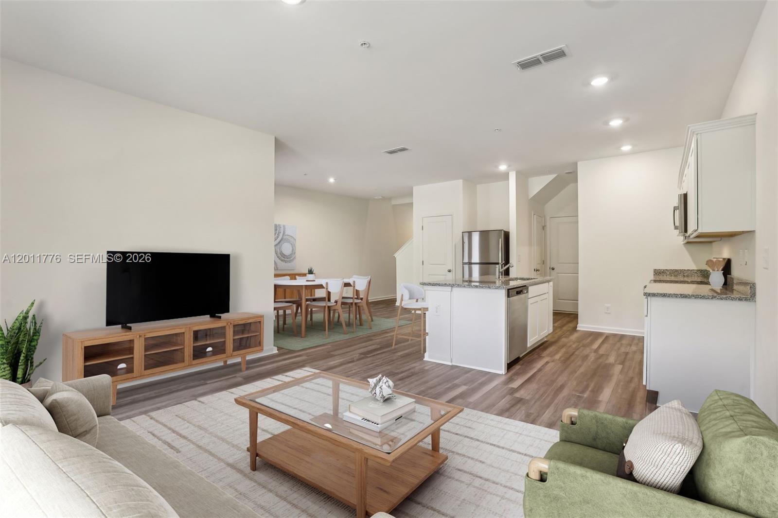 An open-concept living room and kitchen featuring light wood flooring and neutral walls — 2571 GREY HAWK DR, Kissimmee FL 34746, KISSIMMEE, FL