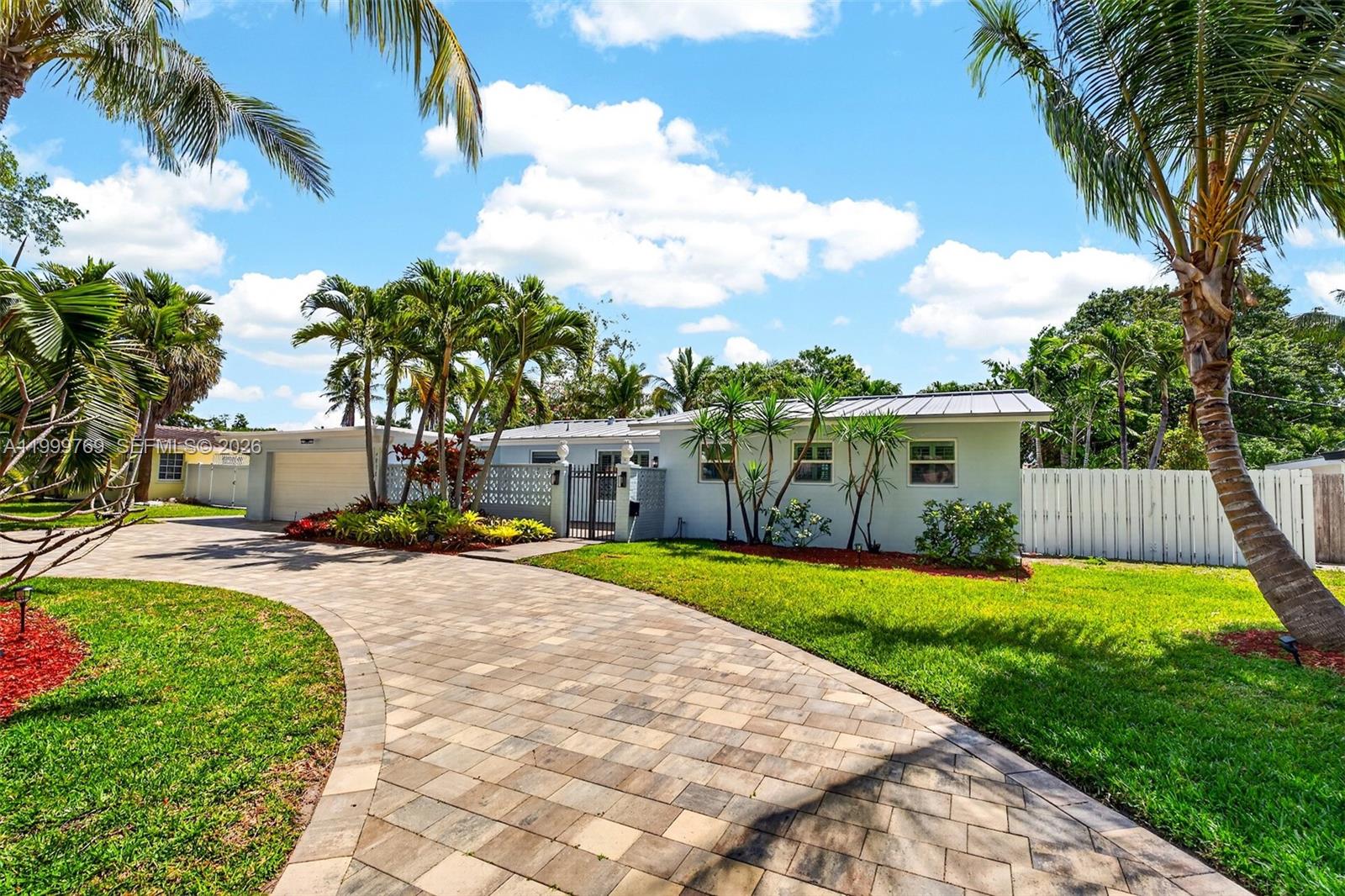 A paved driveway leads to a light-colored single-story house surrounded by palm trees and landscaping — 4010 NE 22nd Ave, Lighthouse Point FL 33064, LIGHTHOUSE POINT, FL