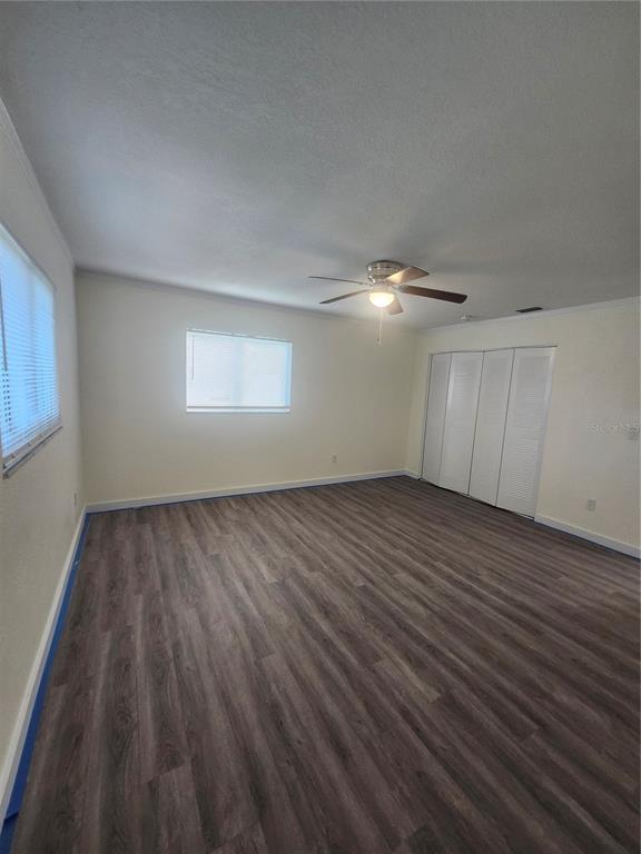 An empty bedroom features light-colored walls, a ceiling fan, and dark wood-look plank flooring — 2441 BEACON DRIVE, PORT CHARLOTTE, FL