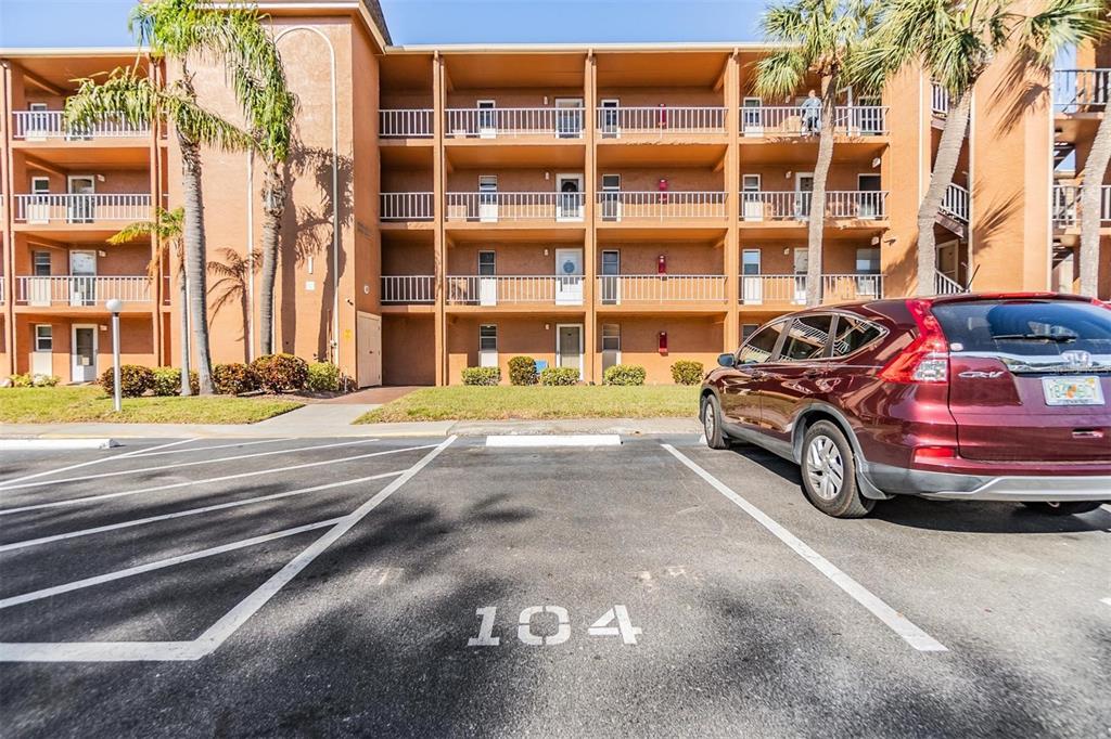 A parking space labeled 104 sits in front of a multi-story apartment building — 12760 INDIAN ROCKS ROAD UNIT 104, LARGO, FL