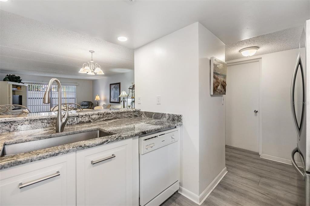 A kitchen with white cabinets, granite countertops, a stainless steel sink, and a dishwasher — 12760 INDIAN ROCKS ROAD UNIT 104, LARGO, FL