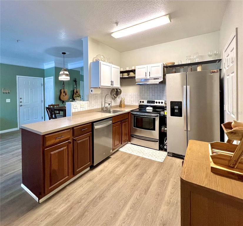 A kitchen features wood cabinets, stainless steel appliances, a breakfast bar, and light-colored flooring — 4802 51ST STREET W UNIT 1315, BRADENTON, FL